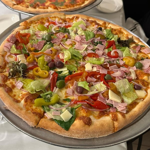 A large Bazzarelli Italian salad pizza with ham, salami, cheese, olives, peppers, and lettuce.