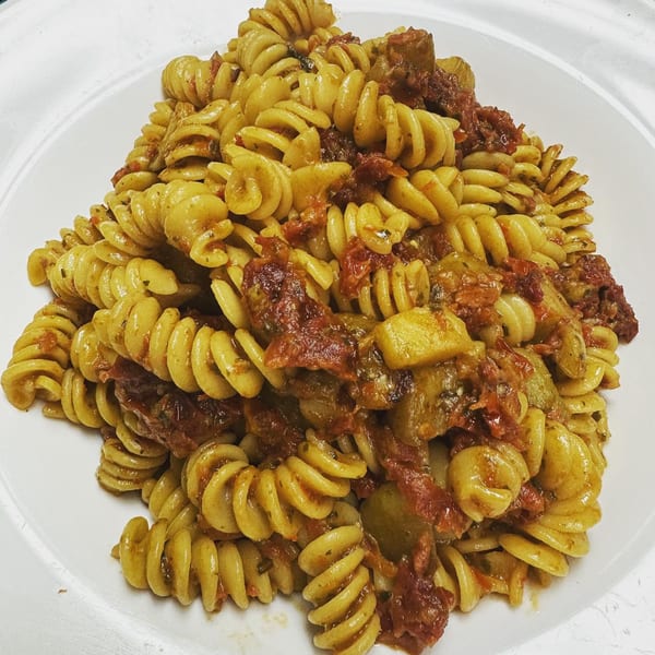 A close-up of Bazzarelli's fusilli pasta with a rich red sauce and vegetables on a white plate.